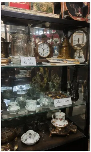 Glass case of pocket knives, clocks, and silver