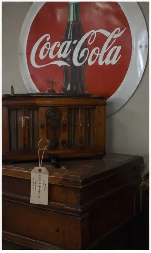 Round Coca-Cola sign behind a wooden radio and trunk